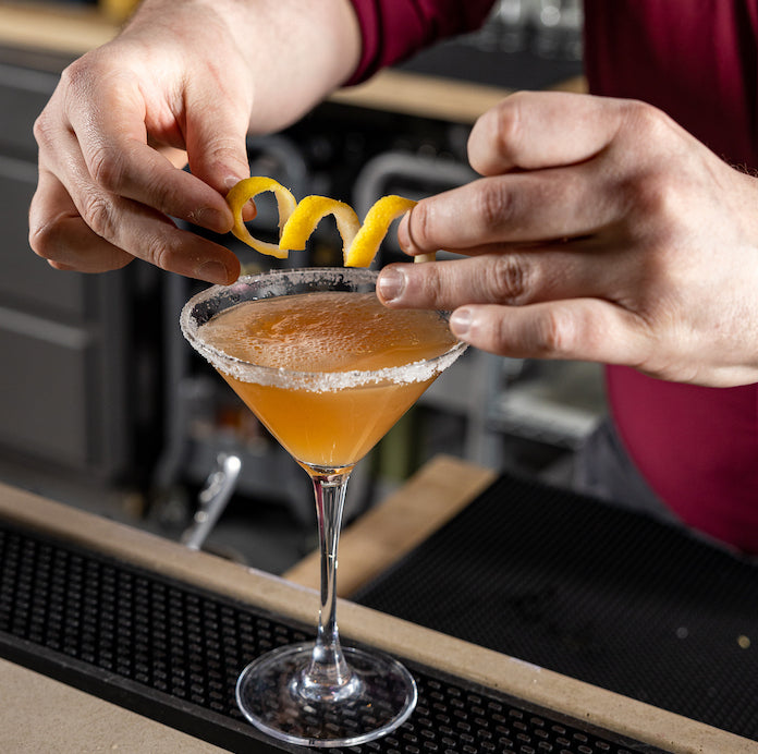man places lemon garnish on cable car cocktail made with Dry Land Distillers Cane Rum